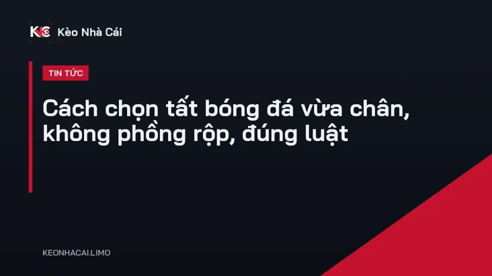 Đôi tất bóng đá dài màu xanh đặt cạnh giày đá bóng và bincluso ống đồng trên sân cỏ